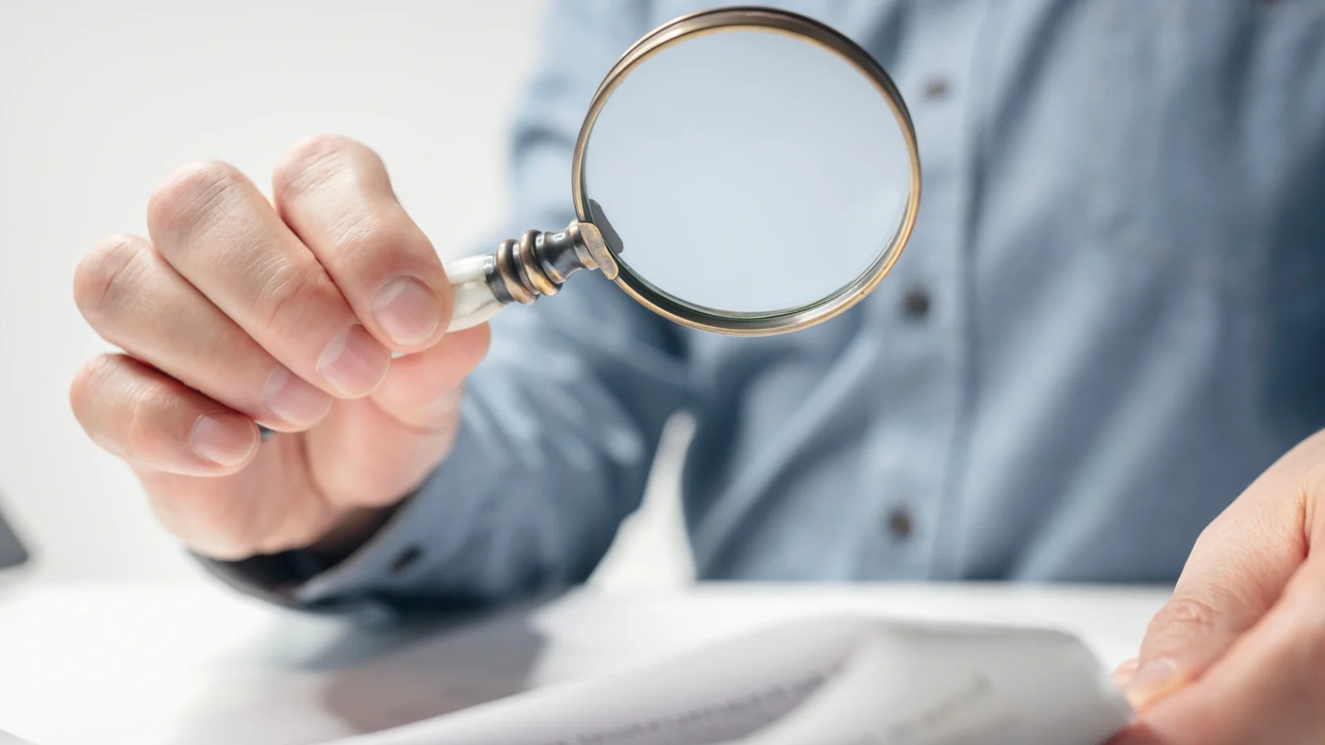 A person reads over warranty documents with a magnifying glass
