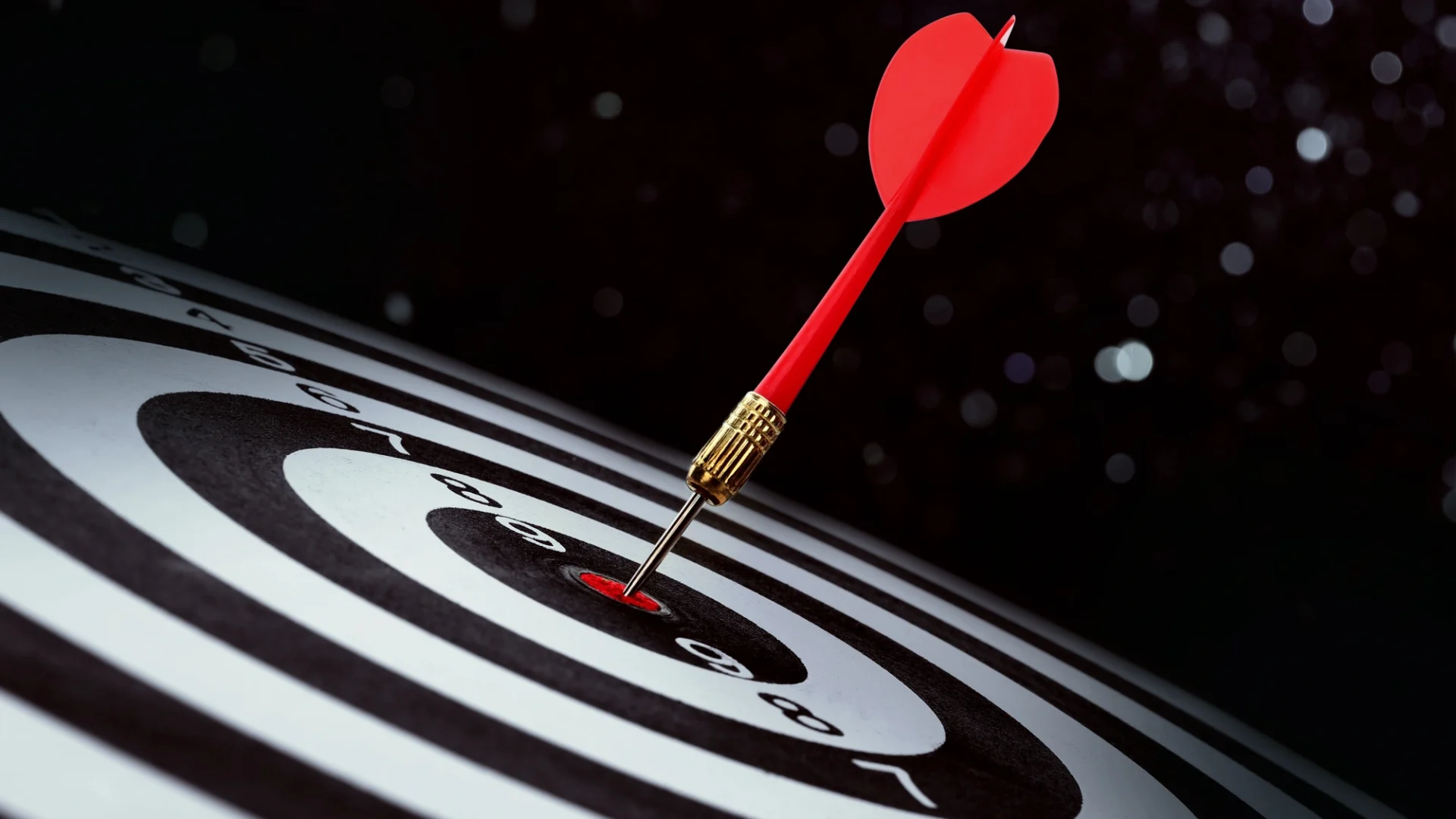 A black and white target with a red dart hitting the bullseye