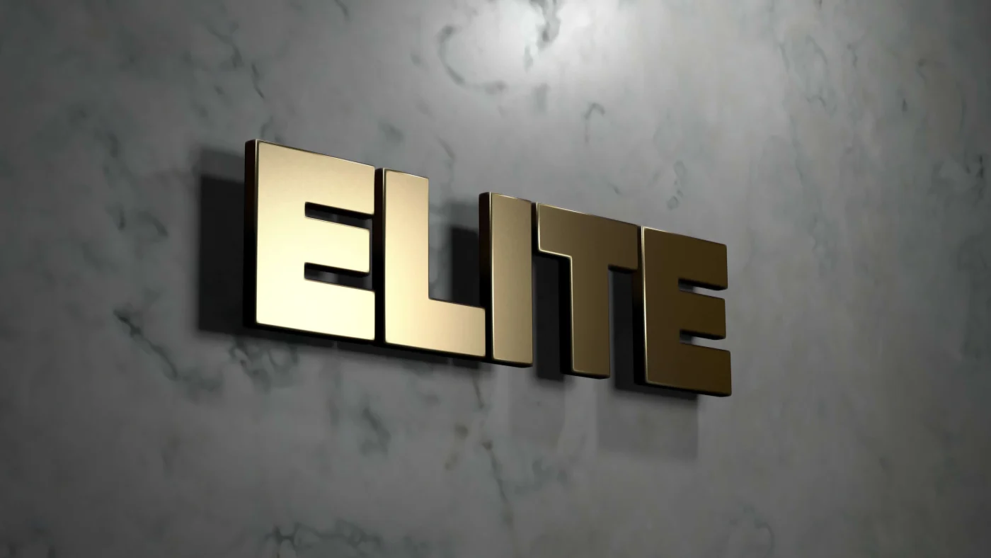 Close view of the word “Elite” made from raised, gold block letters hanging on a marble wall