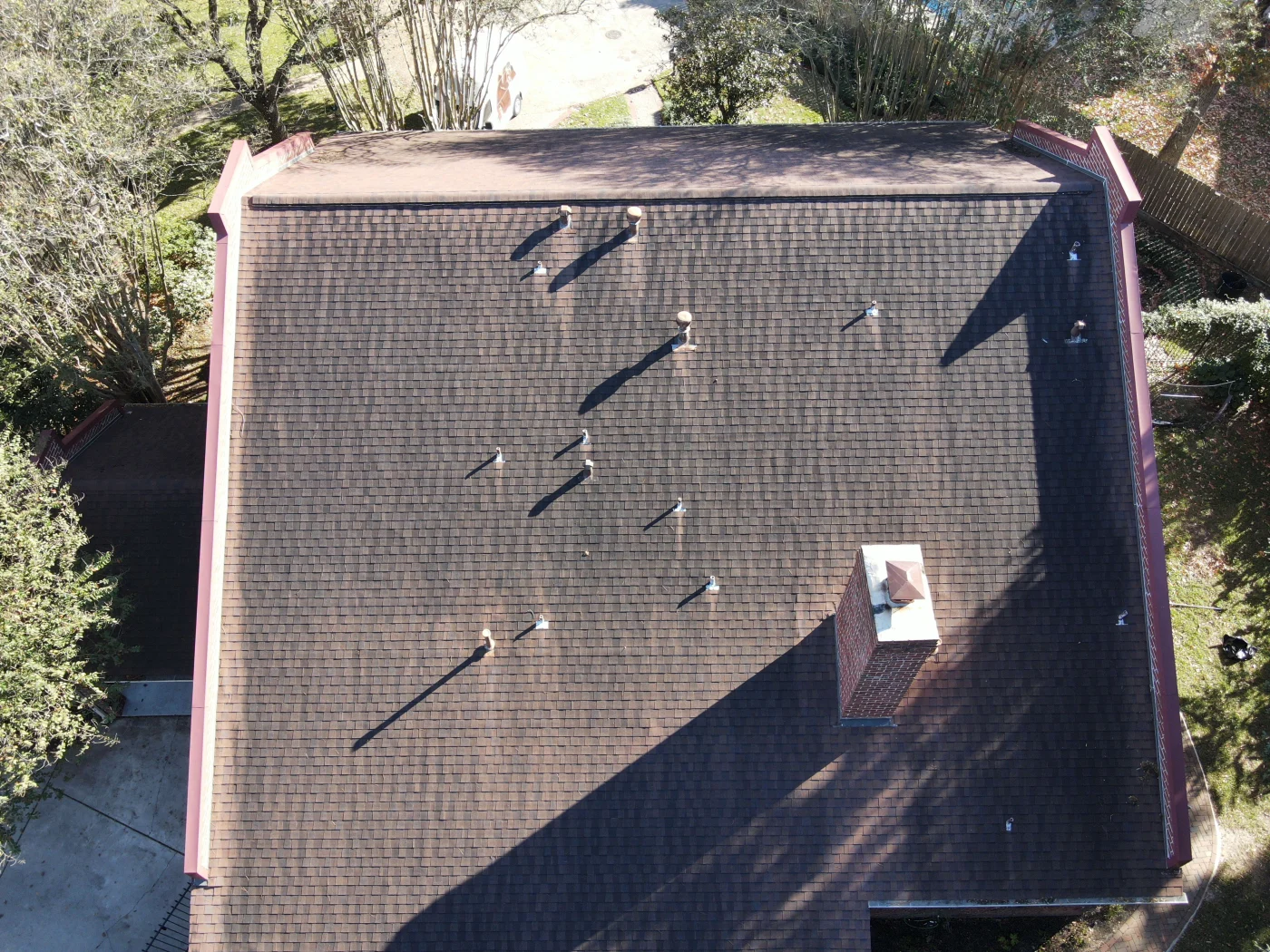 Revitalizing Roof Cleaning | Conroe, TX | Brinkmann Quality Roofing Roof cleaning in Conroe, TX, by Brinkmann Quality Roofing, with a worker pressure washing darkened shingles to restore color and extend roof life.