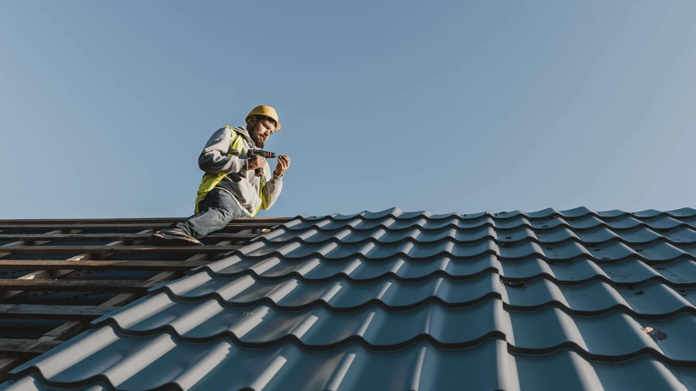 Best Tile Roofing In Clear Lake City, TX | Brinkmann Quality Roofing A worker wearing a vest and a hard hat as he installs new tile roofing on a home.