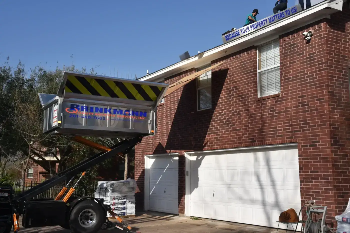 Expert Roof Maintenance | Katy, TX | Brinkmann Quality Roofing Services Roofers utilize a hydraulic debris lift alongside a two-story brick home to streamline efficient roof maintenance and cleanup.