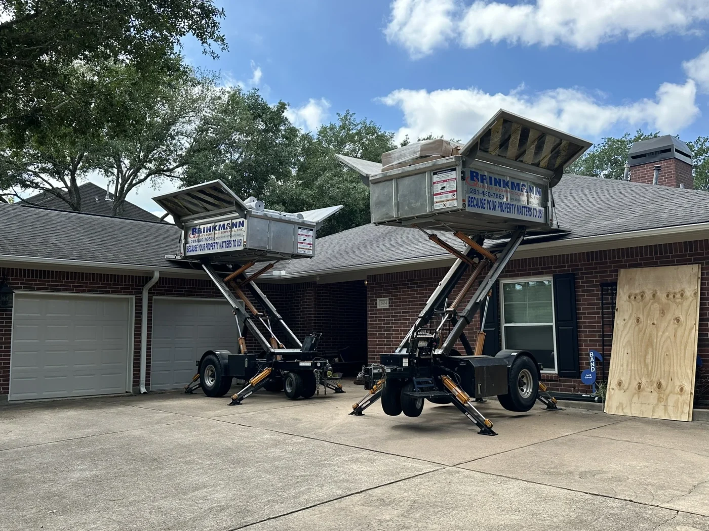 Locally Trusted Roof Maintenance | Katy, TX | Brinkmann Quality Roofing Services Two elevated hydraulic lifts positioned in a driveway streamline the transport and cleanup of heavy materials during a residential roof maintenance project.