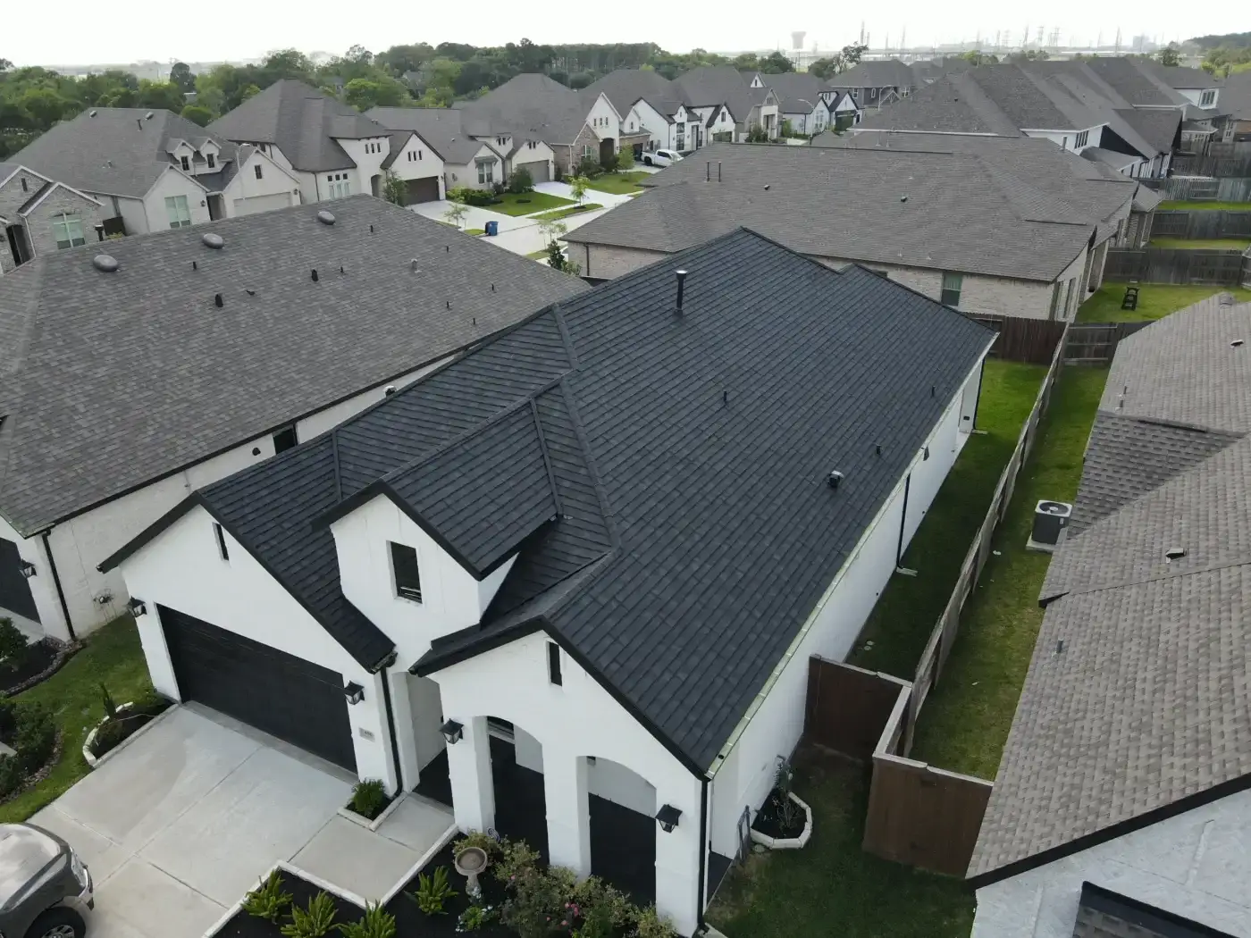 Outstanding Fortified Roofing | Richmond, TX | Brinkmann Quality Roofing Services A fresh black shingle roof stands out in a suburban neighborhood as an example of storm-resistant fortified roofing.