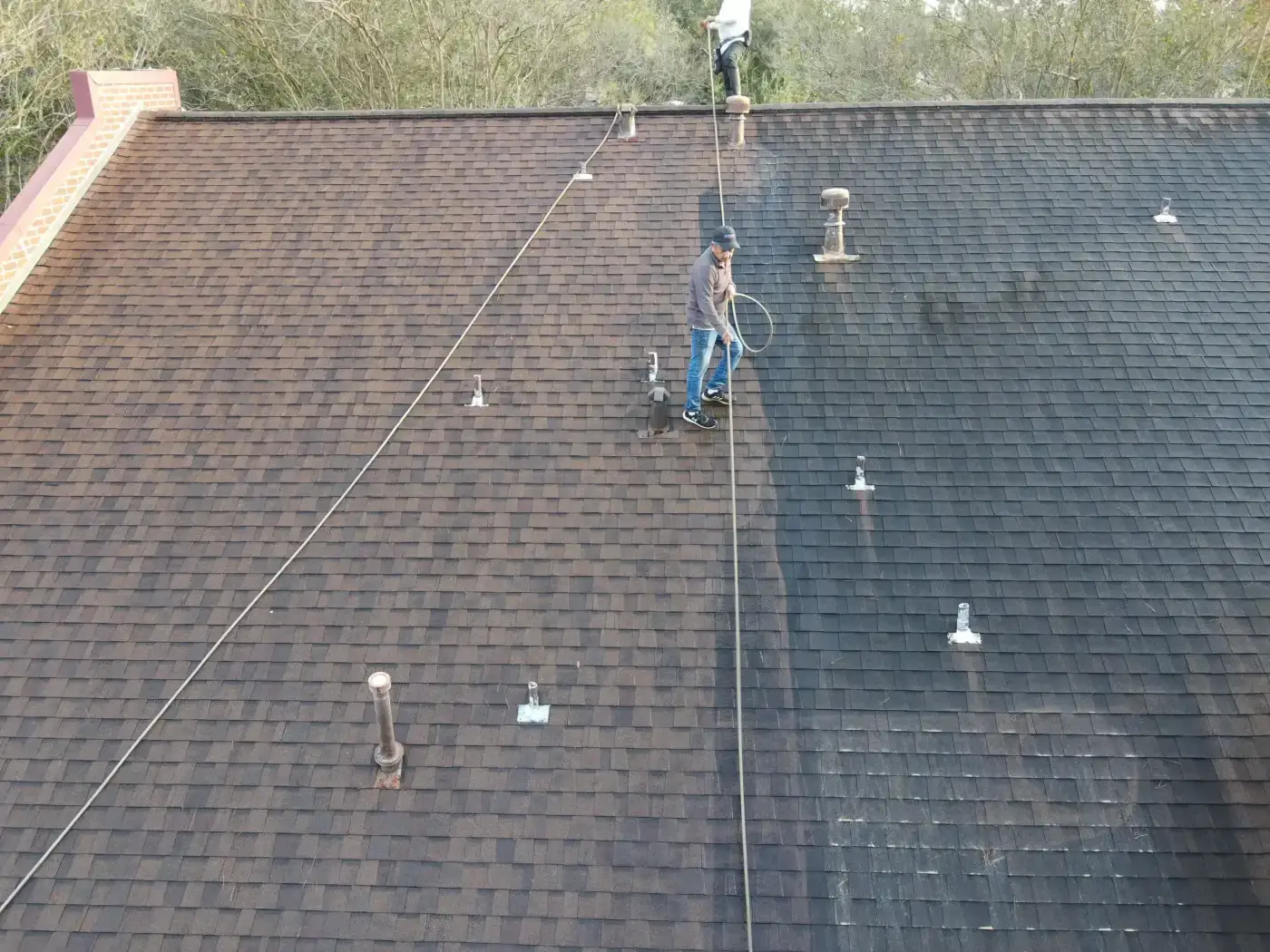 Trusted Roof Cleaning | Katy, TX | Brinkmann Quality Roofing Services A side-by-side contrast reveals the removal of dark staining from asphalt shingles during professional roof cleaning services.