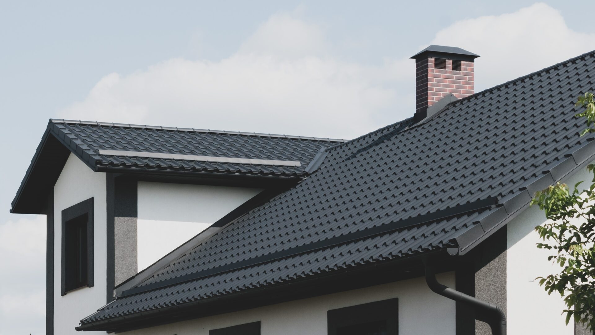 A black metal roof on a white home with black trim