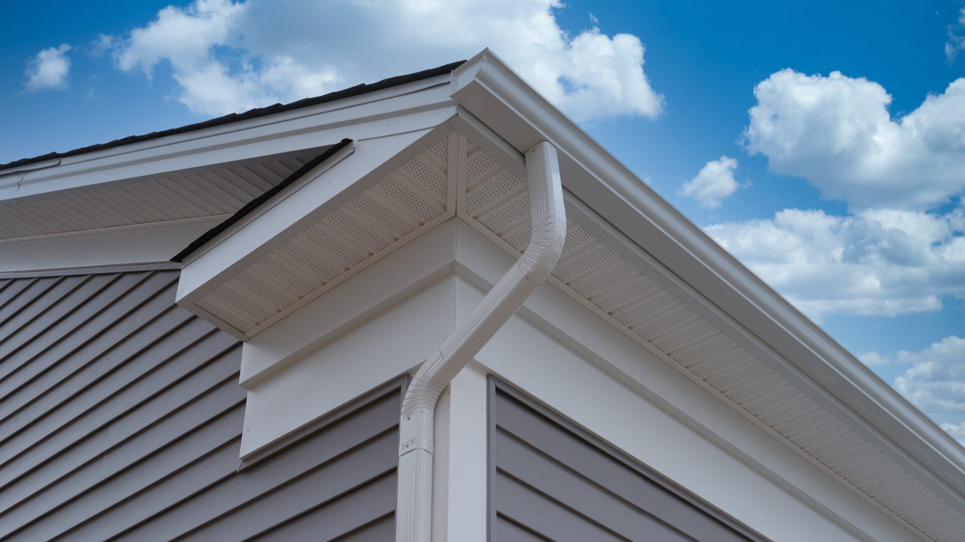 Closeup of a gutter downspout on a gray-sided home