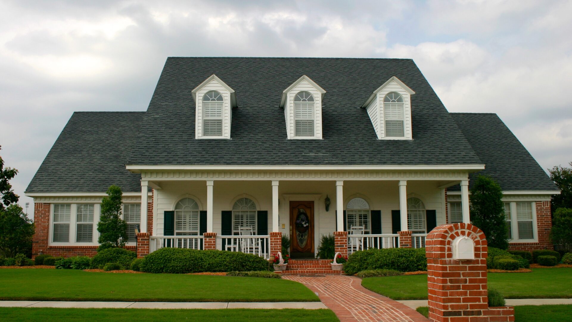 A large home with gray shingle roofing and three dormer windows