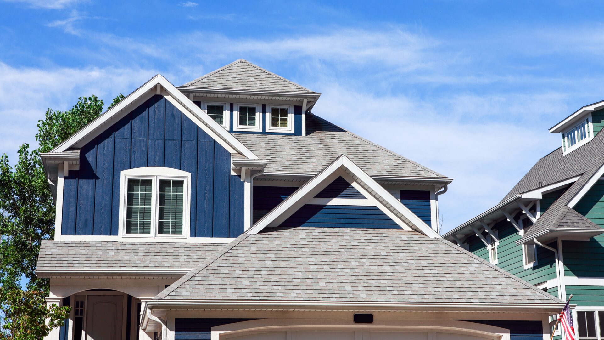 A blue-sided home with gray shingle roofing