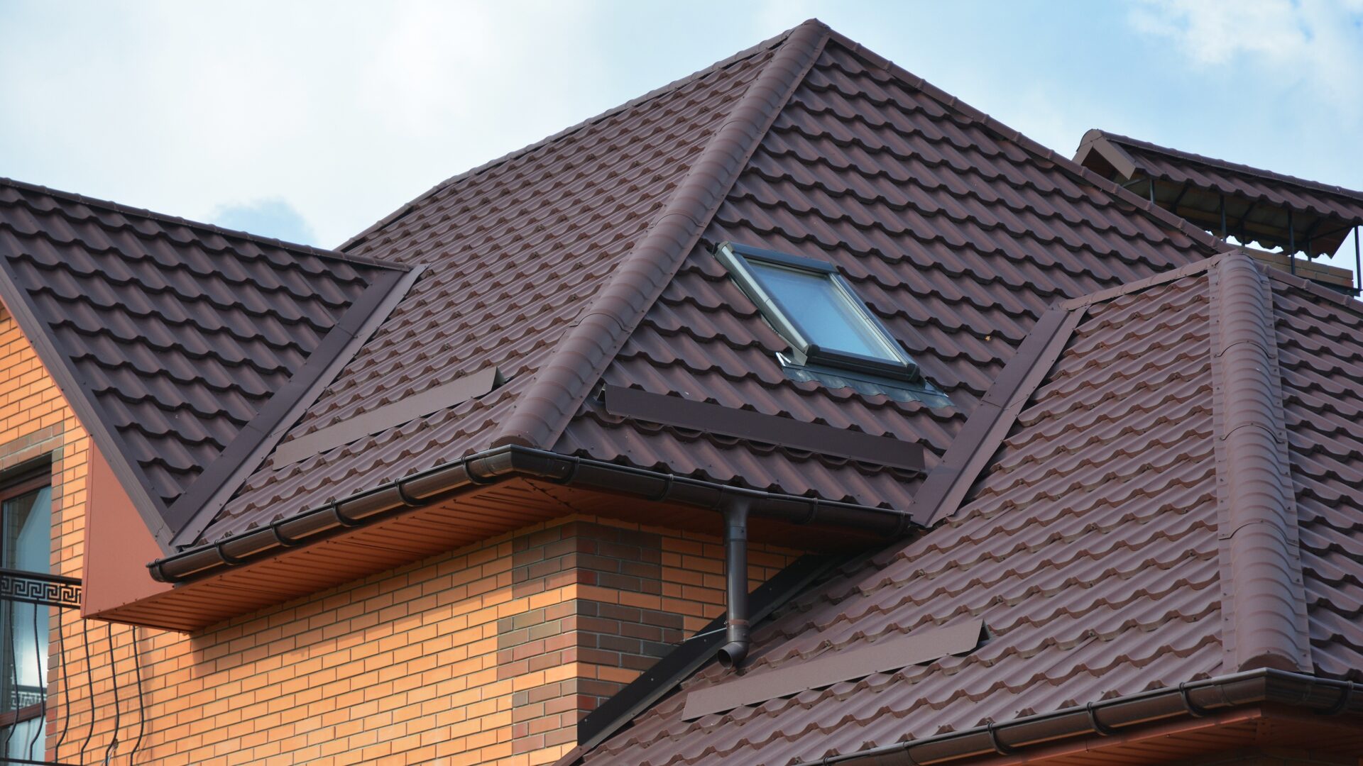 A brown tile roof with a skylight on an orange brick home